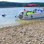 Pontoon Boat and swimmers on lake near shore during Summer