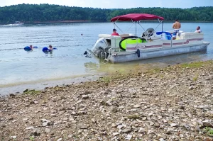 Pontoon Boat and swimmers on lake near shore during Summer