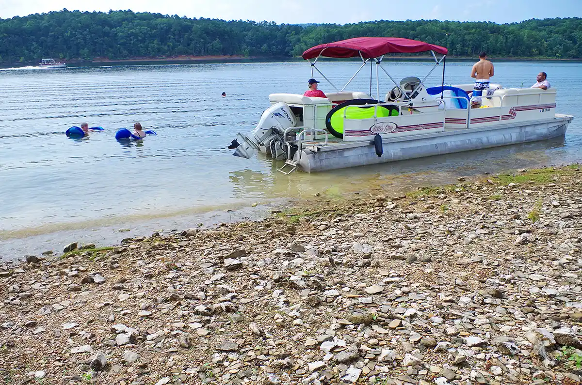 Pontoon Boat and swimmers on lake near shore during Summer